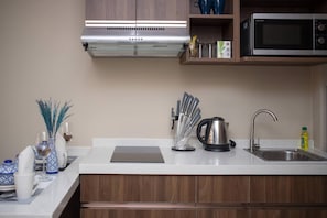 A modern kitchen with a stainless steel range hood, a microwave, and a kettle on the counter.