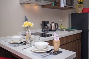 A modern kitchen with a white countertop, a sink, a kettle, and a refrigerator. - Vero Condo 1br | Garden view | nbc nai harn (Rawai)