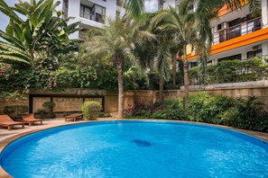A swimming pool surrounded by lush greenery and a building with balconies. - Vero Condo 1br | Garden view | nbc nai harn (Rawai)