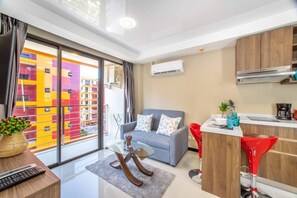 Een modern appartement met balkon, een bank, een eethoek en een keuken.