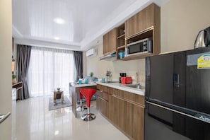 Una cocina moderna con un refrigerador negro, armarios de madera y un microondas.