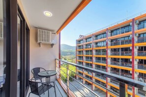 A balcony with a table and chairs, overlooking a multi-story building with balconies.