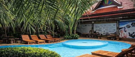 A pool area with wooden loungers and a mural on the wall.