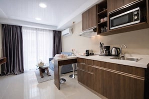 A modern kitchen with a built-in microwave, a sink, and wooden cabinets. - Kai Condo 1br | Pool view | nbc nai harn (Rawai)