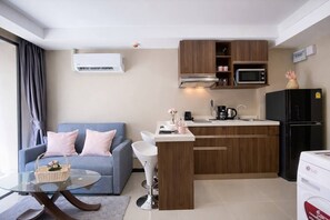 A compact living space with a kitchenette, a sofa, a coffee table, and a refrigerator.
