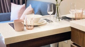 Et pænt anrettet spiseområde med et bord dækket til to personer, inklusiv tallerkener, glas og en vase med blomster.