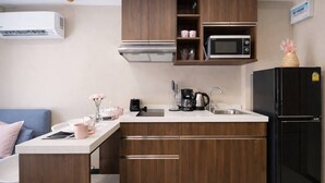 Et lille køkken med mikroovn, kaffemaskine og køleskab.