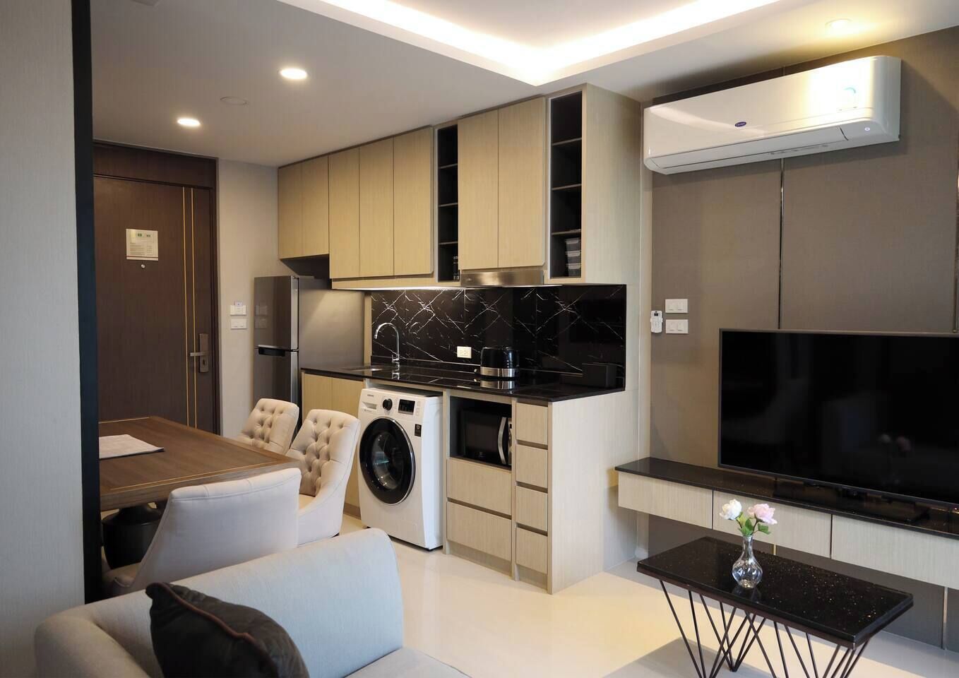 A compact living space with a dining area, kitchen, and a flat-screen TV.