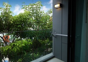 Un balcon offrant une vue sur une végétation luxuriante et un ciel dégagé.