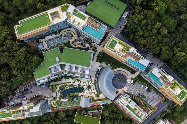 Vue aérienne d’un hôtel doté de plusieurs piscines, de vastes pelouses verdoyantes et d’une cour centrale circulaire.