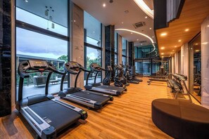Une salle de sport équipée de tapis de course, de vélos d’exercice et d’appareils de musculation.