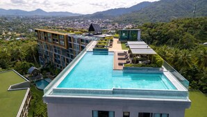 Una piscina sul tetto con vista su un paesaggio urbano e montagne sullo sfondo.