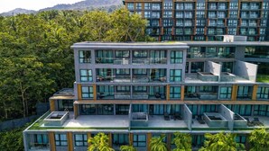 Un hotel a più piani con balconi, ampie finestre e un ambiente verde e rigoglioso.