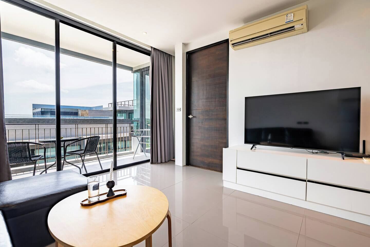Una habitación de hotel moderna con balcón, televisión de pantalla plana y zona de comedor.