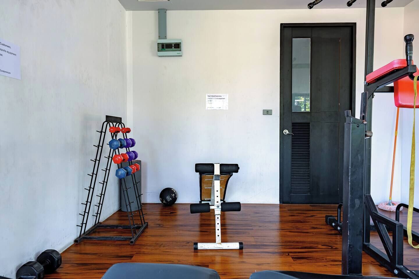 Un gimnasio con equipo de ejercicio, una puerta y un dispositivo montado en la pared.