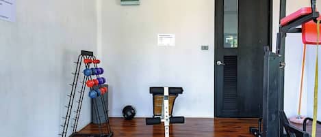 A gym with exercise equipment, a door, and a wall-mounted device.