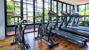 Een sportschool met loopbanden, een crosstrainer en een hometrainer.