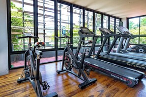 Un gimnasio con cintas de correr, elíptica y bicicleta estática.