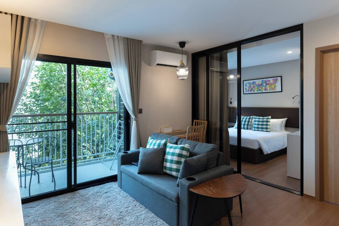 Une chambre d’hôtel moderne dotée d’un balcon, d’un canapé, d’une petite table, d’un lit et d’une porte-fenêtre coulissante.