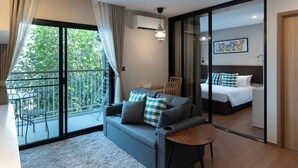 Habitació d'hotel moderna amb un balcó, un sofà, una taula petita, un llit i una porta corredissa de vidre.