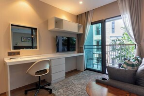 A modern apartment with a desk, a chair, a flat-screen TV, a sofa, and a balcony with a view of the city.