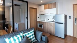 A compact living space with a kitchenette, a sofa with checkered cushions, and a dining area.