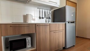 A kitchen with a microwave, a refrigerator, and wooden cabinets.