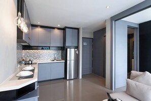 A modern kitchen with grey cabinets, a stainless steel refrigerator, and a tiled backsplash.