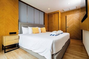Una habitación de hotel moderna con una cama grande, una mesita de noche y un armario.