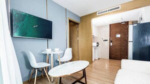 Een moderne hotelkamer met een zithoek, een bank, een televisie en een kitchenette.