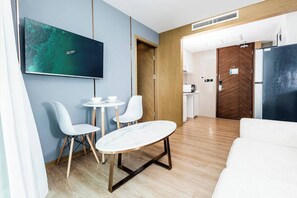 Una habitación de hotel moderna con comedor, sofá, televisor y kitchenette.