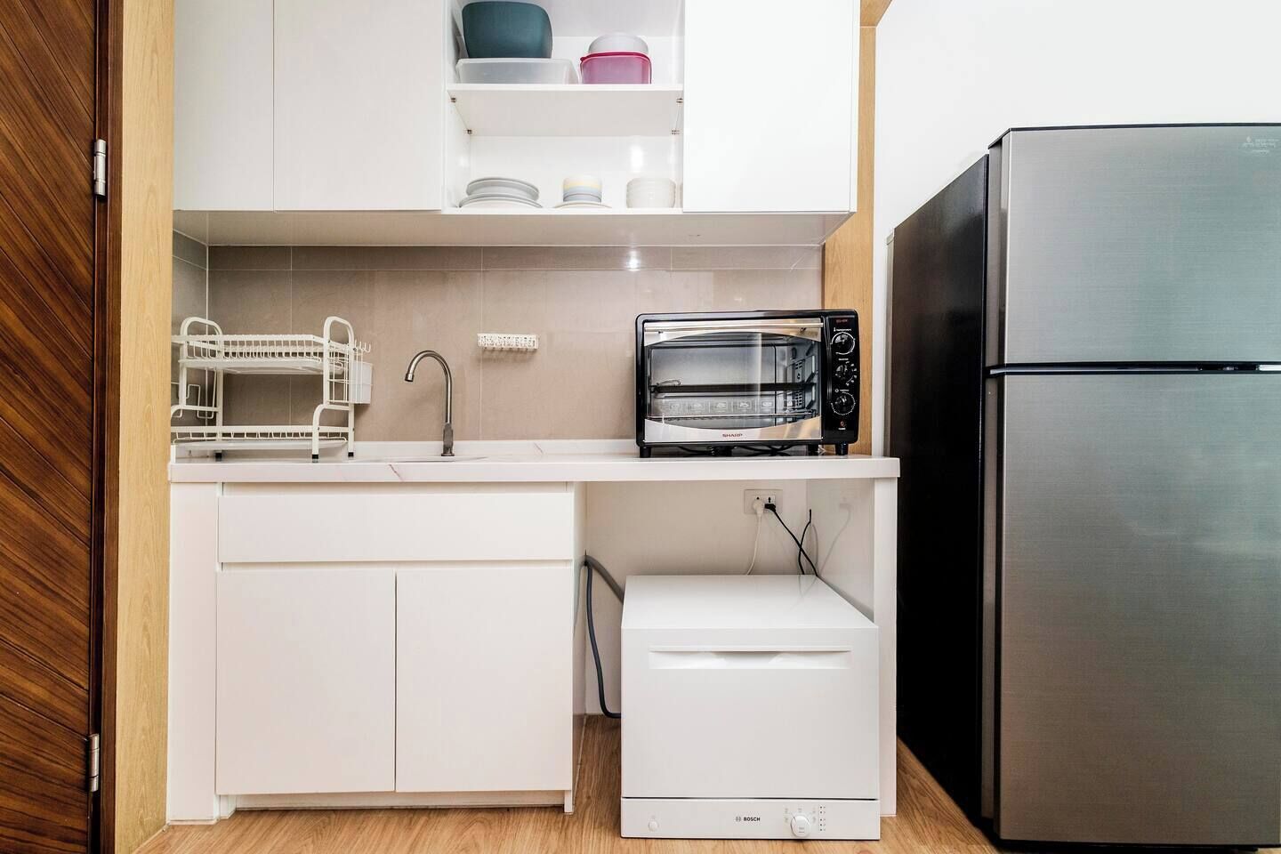A kitchen with a Bosch microwave, a Bosch dishwasher, and a stainless steel refrigerator.