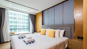 Een hotelkamer met een groot bed, een houten nachtkastje, een raam met gordijnen en uitzicht op een gebouw.