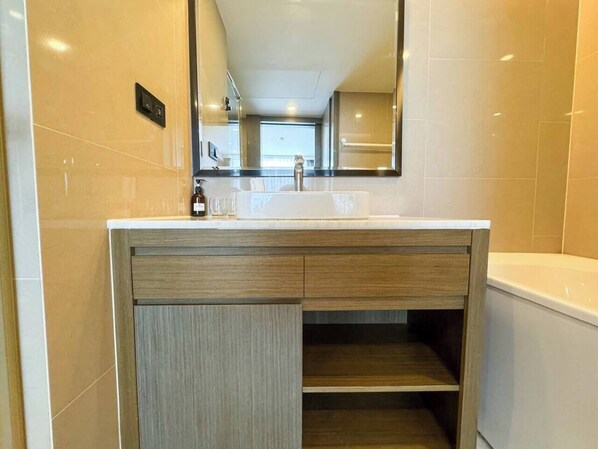Une salle de bain avec un lavabo blanc, un meuble-lavabo en bois et un miroir au-dessus.