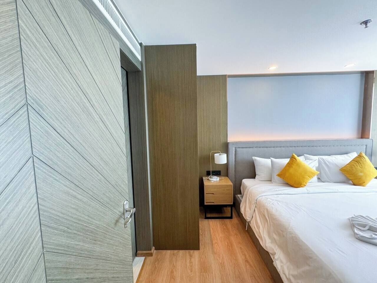 Ein Hotelzimmer mit Bett, Nachttisch, Lampe und Blick zum Himmel.