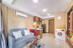 Un espacio habitable pequeño con sofá, lavadora y kitchenette.