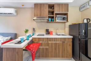A compact kitchen with wooden cabinets, a microwave, a coffee maker, and a refrigerator.