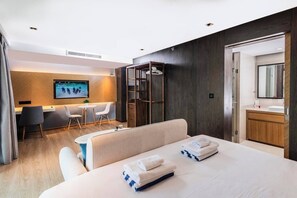 A hotel room with a bed, a desk, a chair, a small table, and a wardrobe. - Studio Aurel 1br|tropical Views|shuttle to Naiharn (Rawai)