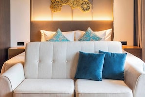 A hotel room with a bed, a sofa, and decorative wall panels.