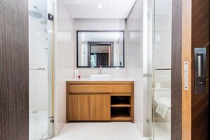 A modern bathroom with a wooden vanity, a large mirror, and a glass shower enclosure. - Studio Aurel 1br|tropical Views|shuttle to Naiharn (Rawai)