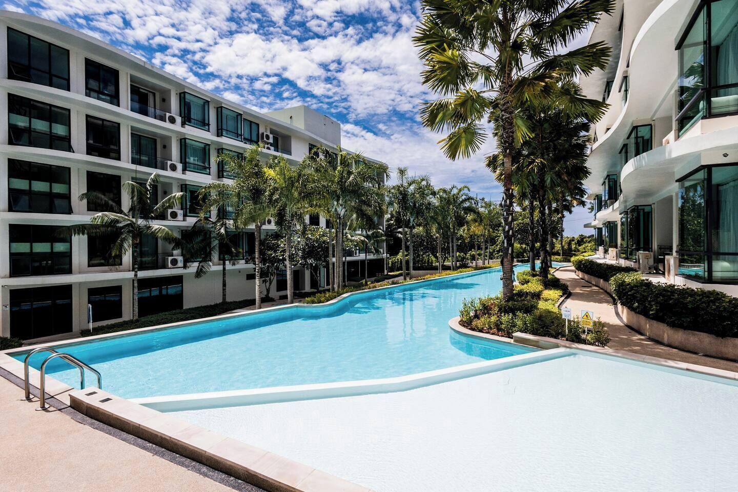 Una piscina rodeada de edificios modernos y palmeras.