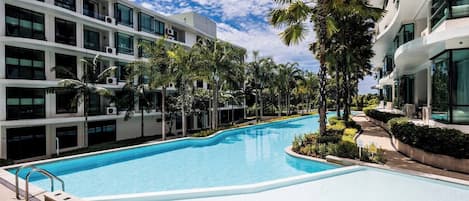 A swimming pool surrounded by modern buildings and palm trees.