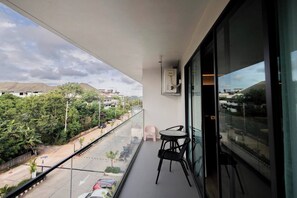 A balcony with a glass railing, a small table, and two chairs.