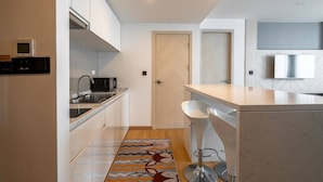Een moderne keuken met een ingebouwde magnetron, spoelbak en een bar met krukken.