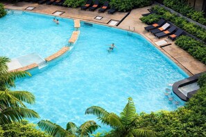 Une piscine au design incurvé, entourée de chaises longues et de palmiers.