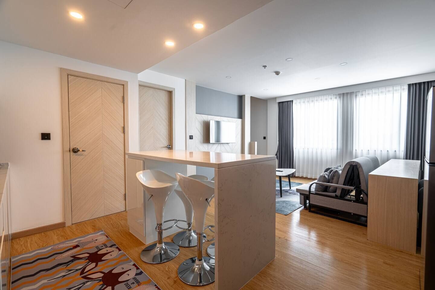 A modern living room with a sofa, a coffee table, and a TV mounted on the wall.
