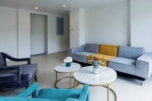 Una sala de estar moderna con un sofá gris, dos mesas redondas, un sillón negro y un sillón azul.