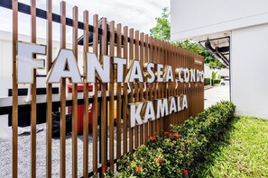 A sign for FANTASEA CONDOMINIUM KAMALA with a modern design and a view of the building's entrance.
