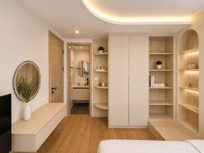 A modern bedroom with a bed, a TV, a wardrobe, and a bathroom visible through an open door.