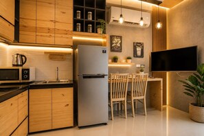 Una cocina moderna con armarios de madera, un refrigerador de acero inoxidable, un microondas y un comedor con dos sillas y una mesa.